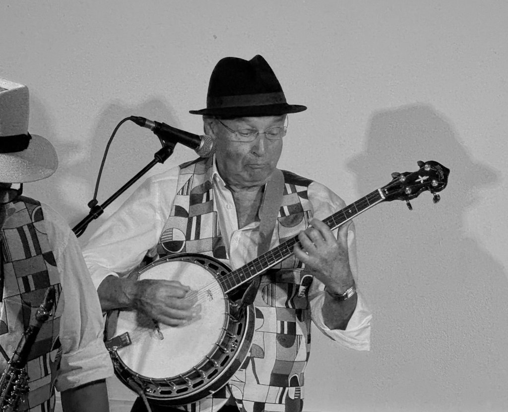 Le banjoïste de Jazz Tico, chapeau noir, devant un micro