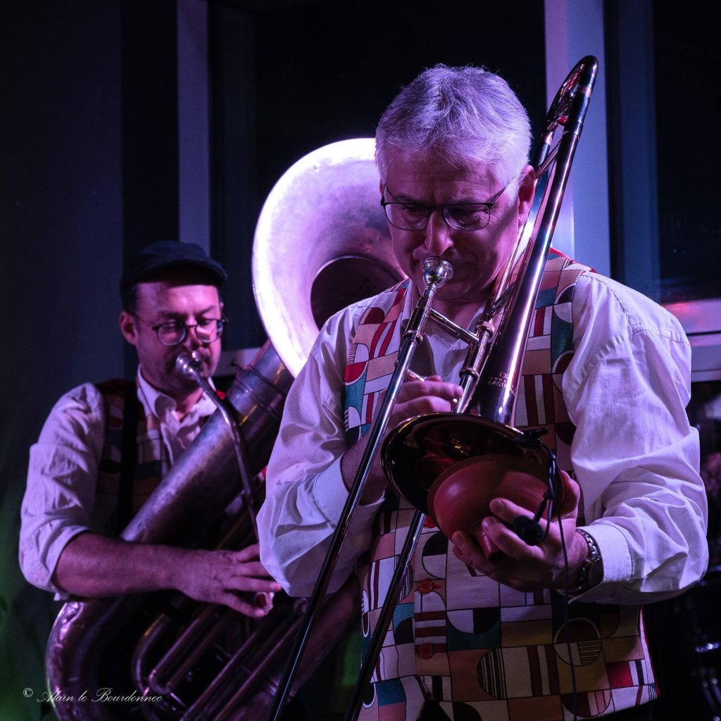 Le tromboniste de Jazz Tico joue avec une sourdine, le joueur d'hélicon en arrière-plan