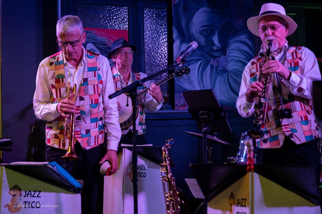 Trompette, banjo et saxophone de Jazz Tico sur scène, derrière les pupitres marqués Jazz Tico