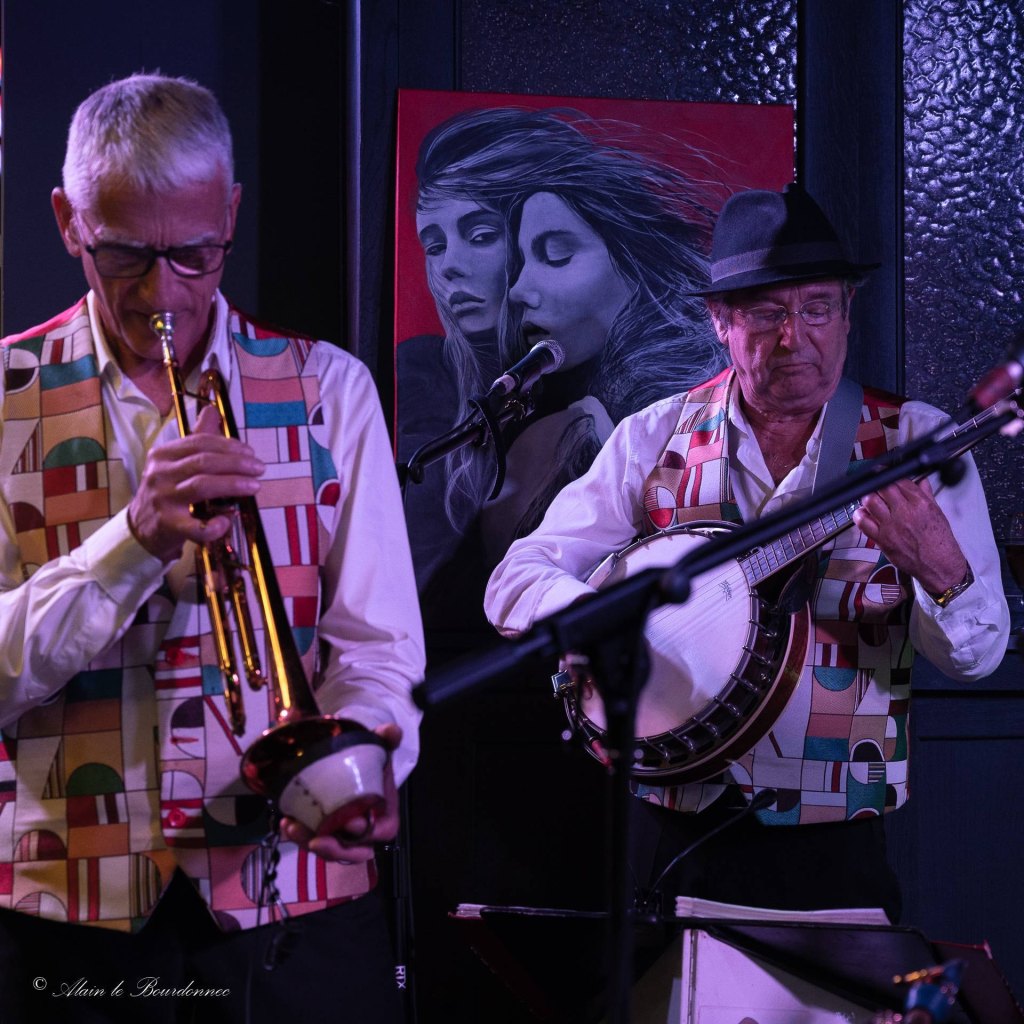 Le trompettiste, sourdine à la main, et le banjoïste de Jazz Tico devant un tableau rouge