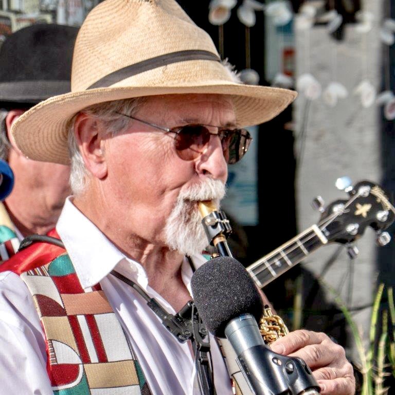 Le saxophoniste de Jazz Tico, chapeau de paille et lunettes de soleil, joue devant un micro