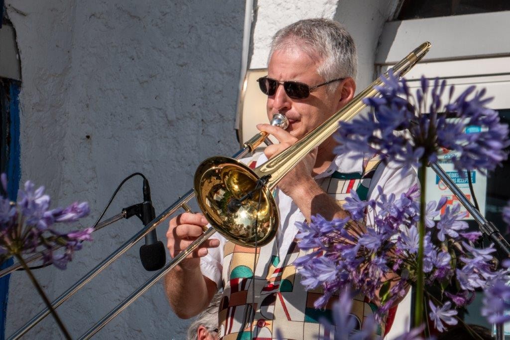 Le tromboniste de Jazz Tico joue au soleil derrière un bouquet d'agapanthes